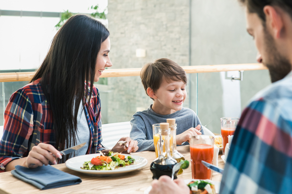 Junge Familie am Tisch in Bistro mit Essen und Getränken