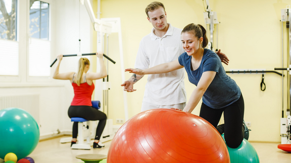Ein Physiotherapeut unterstützt eine Patientin während einer Übung.